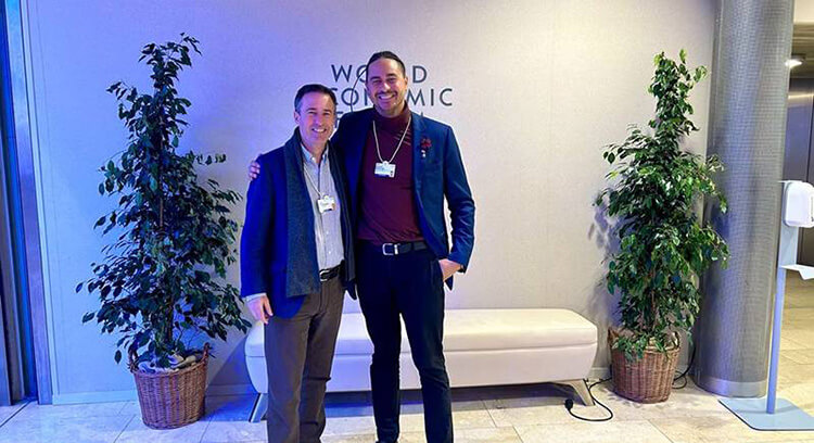 Image of Davos event - two people pose together standing at the World Economic Forum with text in background