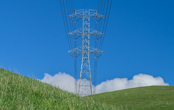 Hydro wire tower within a grass field and blue sky image